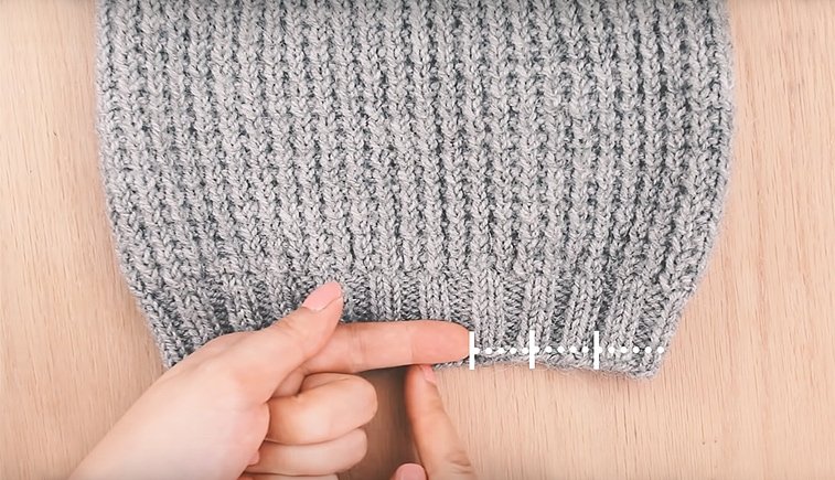 finger measuring a knit hat