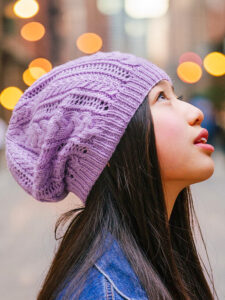 girl wearing a purple knit hat with cables and lace