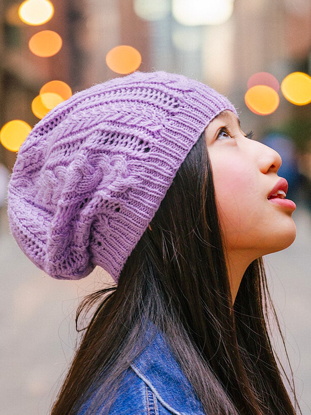 girl wearing a purple knit hat with cables and lace